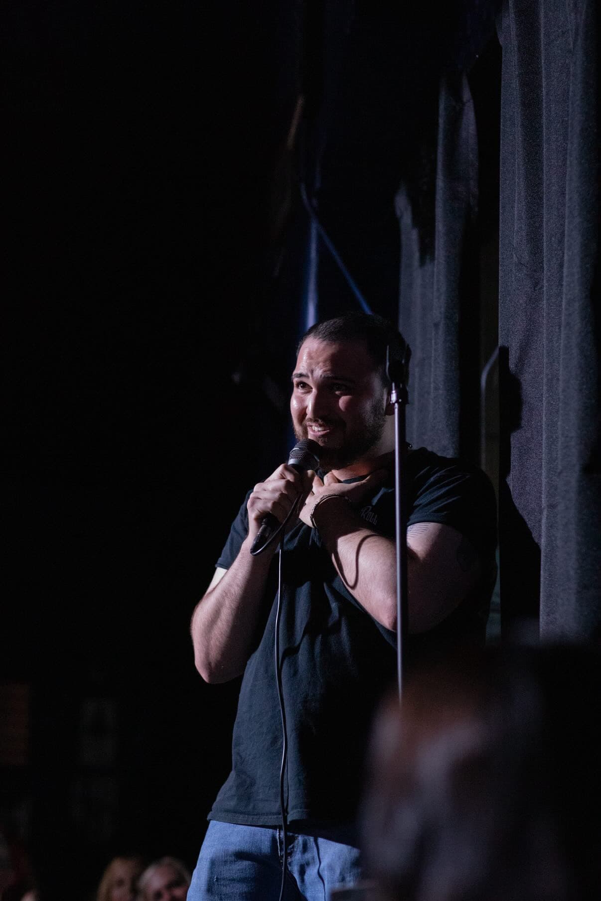 Fumio Flores on stage, mic in hand under a spotlight